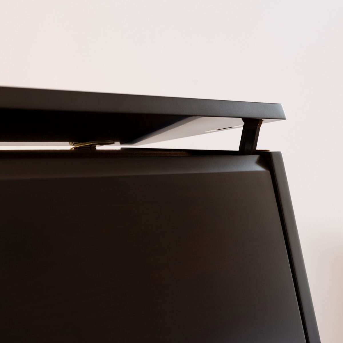Close-up of an upright piano lid with a polished ebony finish, showcasing refined craftsmanship.