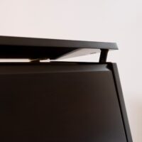 Close-up of an upright piano lid with a polished ebony finish, showcasing refined craftsmanship.