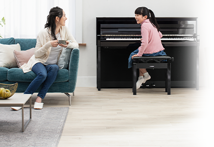 Woman and girl enjoying music with a Yamaha upright piano, highlighting home piano experience at Classic Pianos Portland.