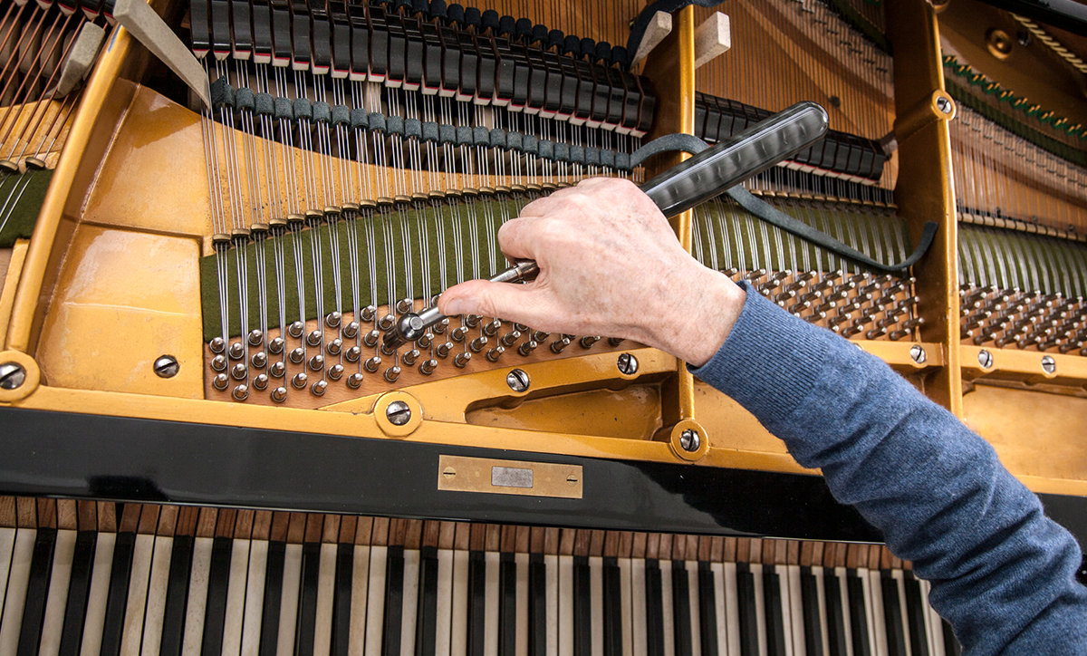 A man tuning a used piano at Classic Pianos
