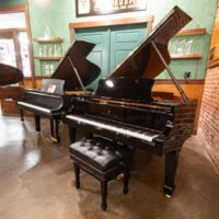 Polished Steinway & Sons grand piano showcasing intricate craftsmanship and sleek ebony finish, paired with a luxurious bench.