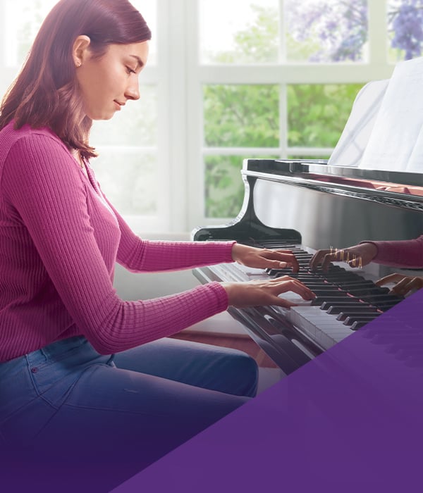 Young pianist playing a polished grand piano, showcasing quality craftsmanship and elegant design at Classic Pianos Portland.