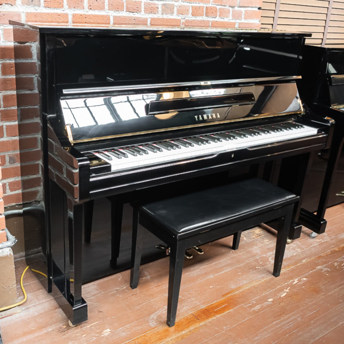 Yamaha black upright piano with polished finish and matching bench, perfect for any home or studio. Ideal for musicians.