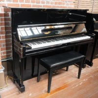 Yamaha black upright piano with polished finish and matching bench, perfect for any home or studio. Ideal for musicians.