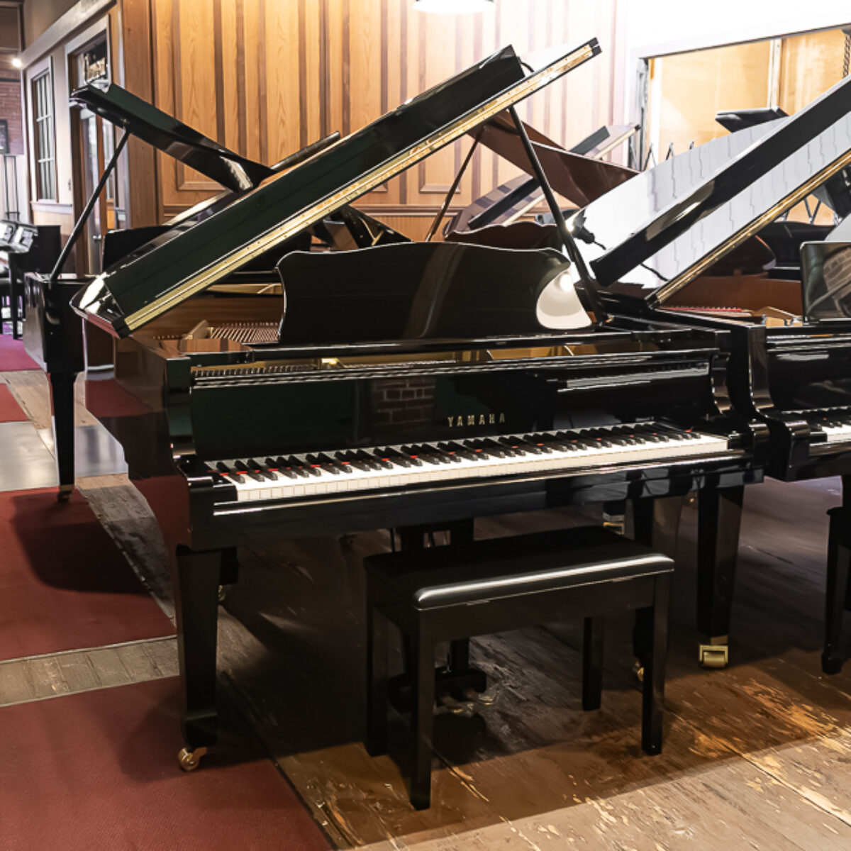 Yamaha upright grand piano featuring polished ebony finish and a matching bench, showcasing exceptional craftsmanship and tone.