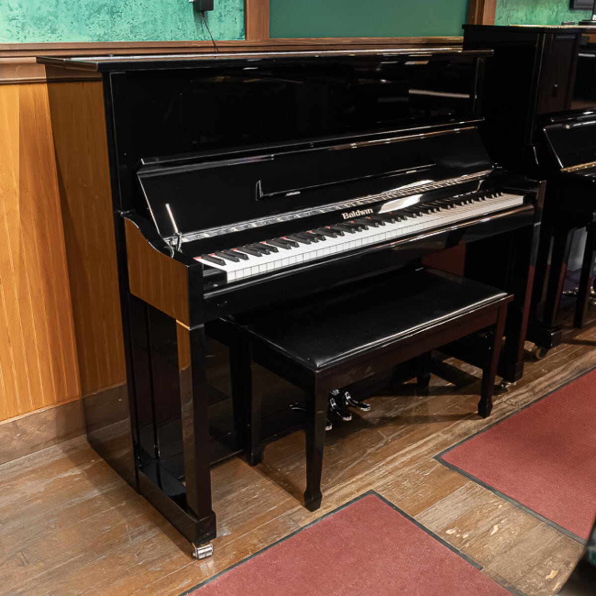 Baldwin upright piano in sleek black finish with matching bench, showcasing quality craftsmanship and classic design.