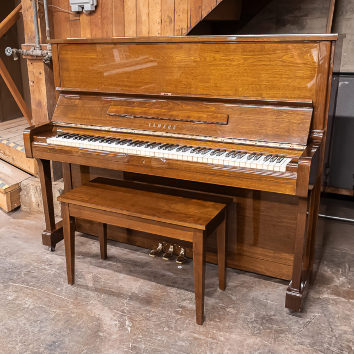 Alt text: Yamaha upright piano in a polished walnut finish, featuring 88 keys and a matching bench, perfect for any home.