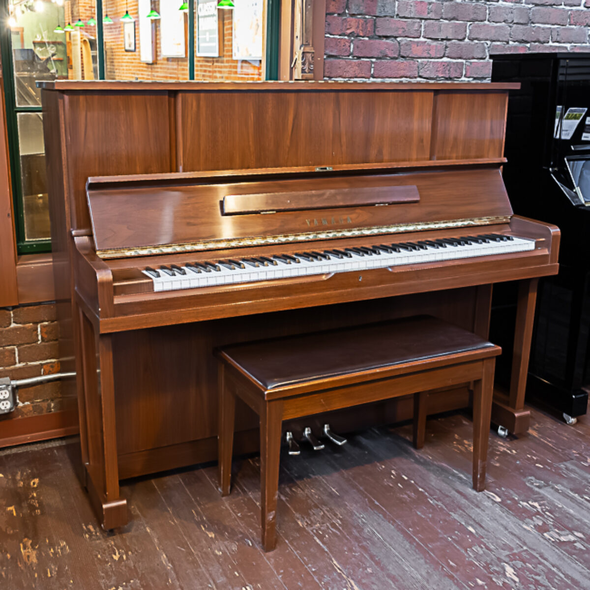 Yamaha upright piano in polished walnut finish with a matching bench, perfect for any music enthusiast.