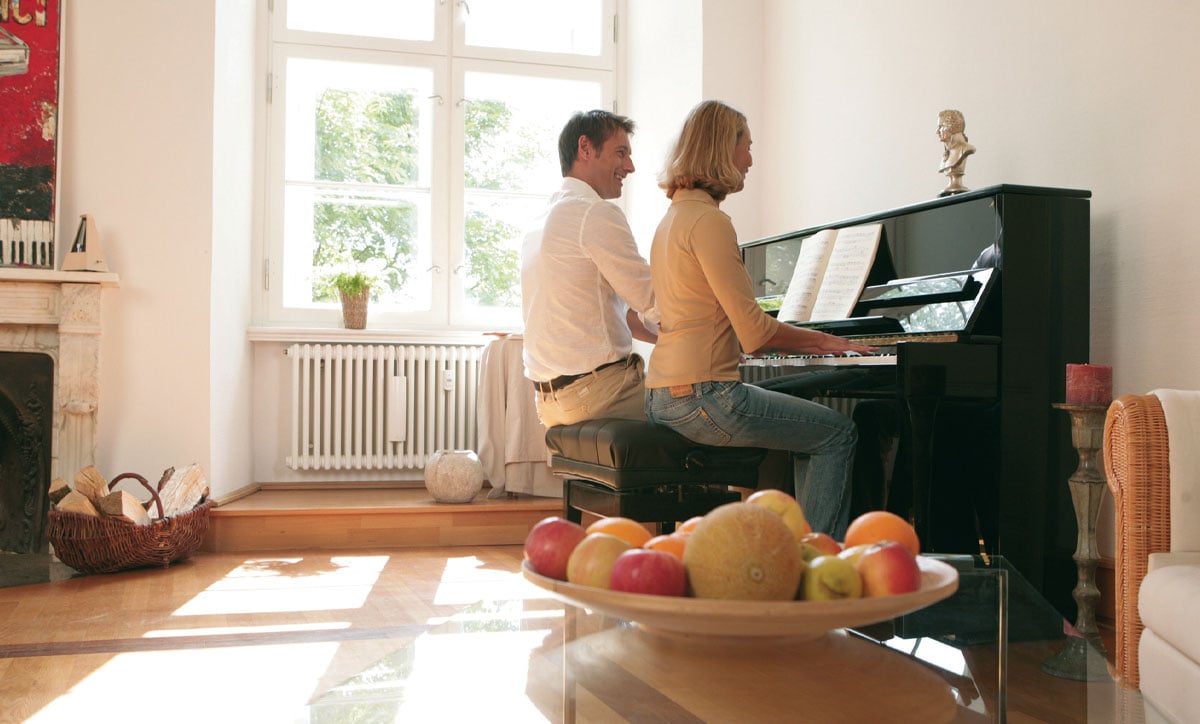 Couple enjoying music together on a stylish black upright piano, highlighting a relaxing home piano experience.