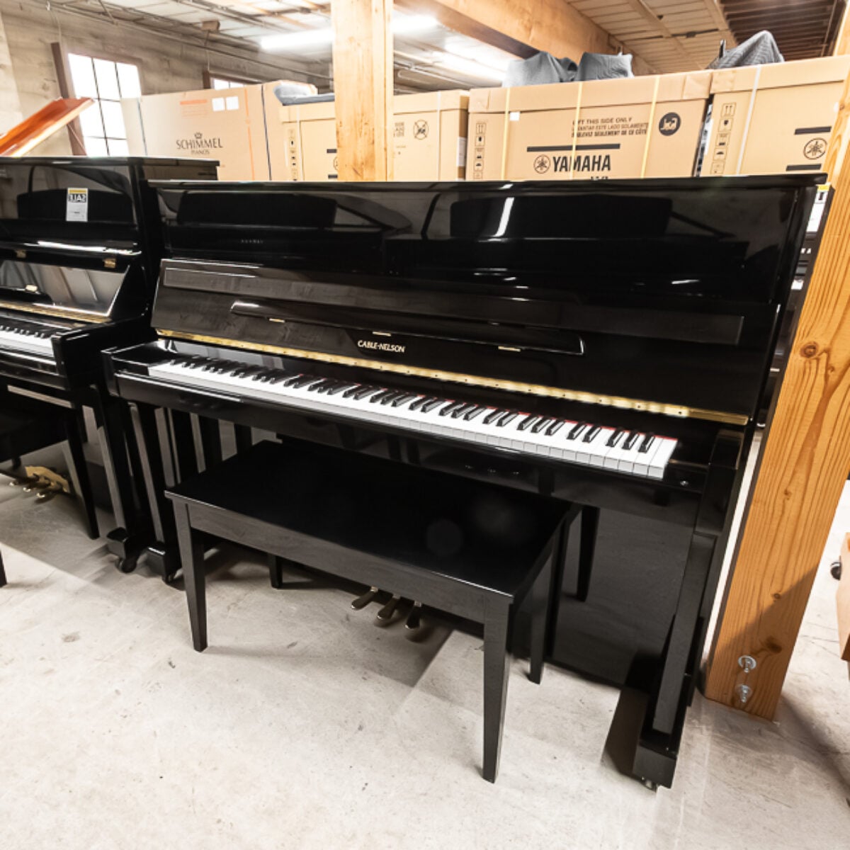 Alt text: Cable Nelson upright piano with polished black finish and matching bench, showcasing premium craftsmanship and design.