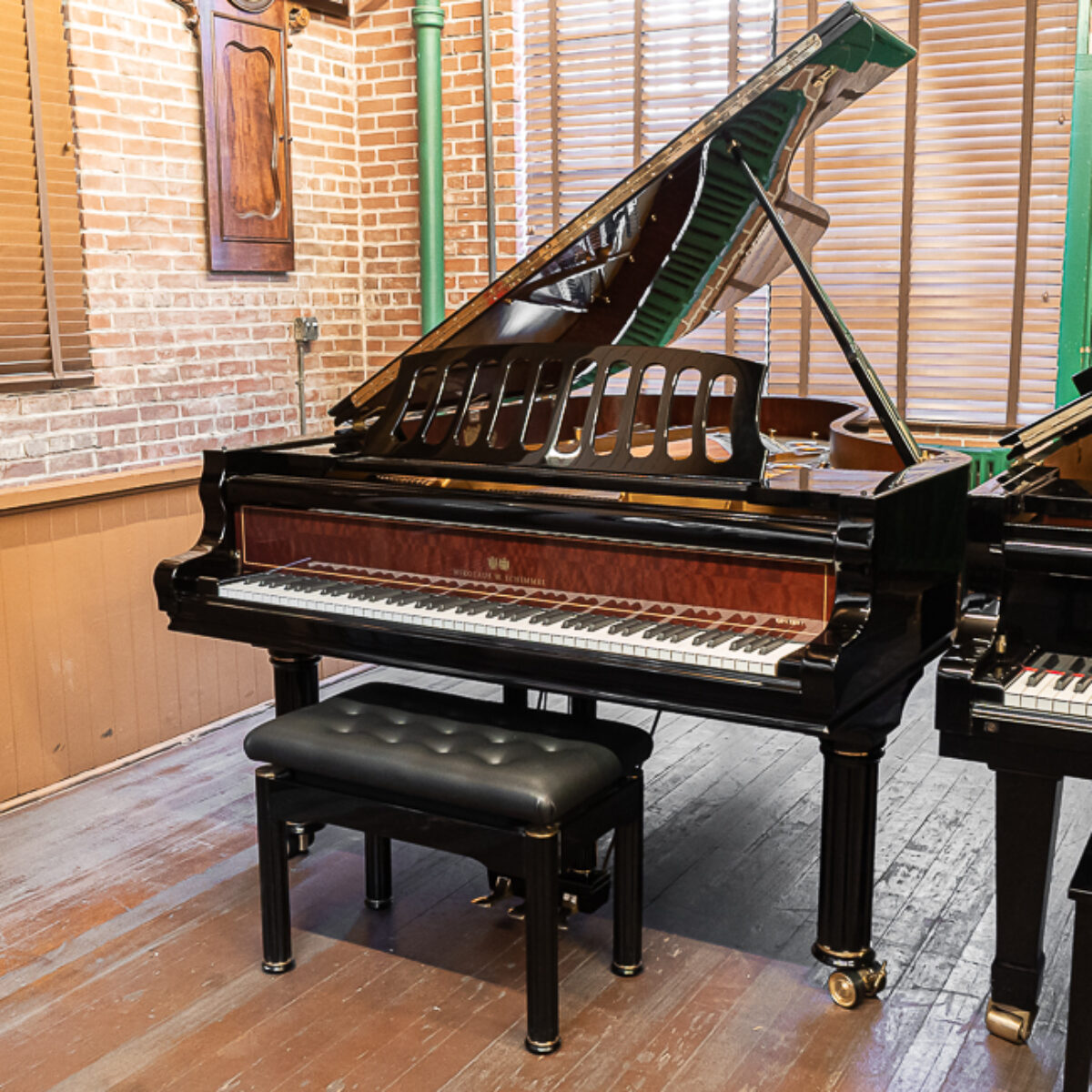 Grand piano in polished ebony finish with rich mahogany accents and a matching deluxe bench, showcasing superior craftsmanship.