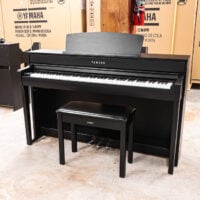 Yamaha digital piano with black finish and matching bench, showcasing premium keys and realistic sound features.
