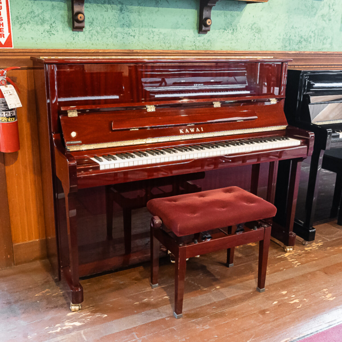 Kawai upright piano in polished mahogany finish, featuring a matching padded bench for optimal playing comfort.