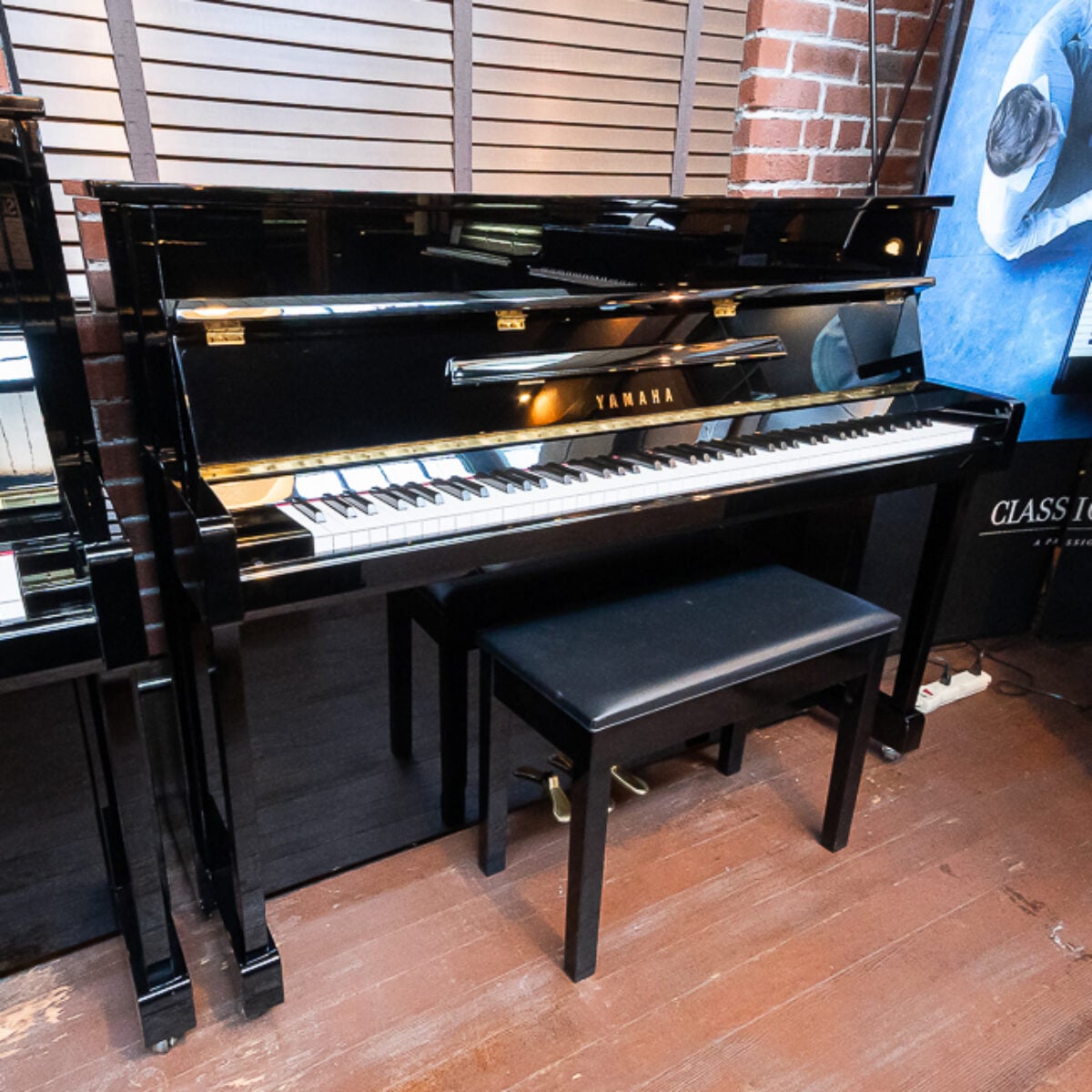 Yamaha upright piano in polished ebony finish, featuring premium keys and a matching bench, ideal for any music enthusiast.