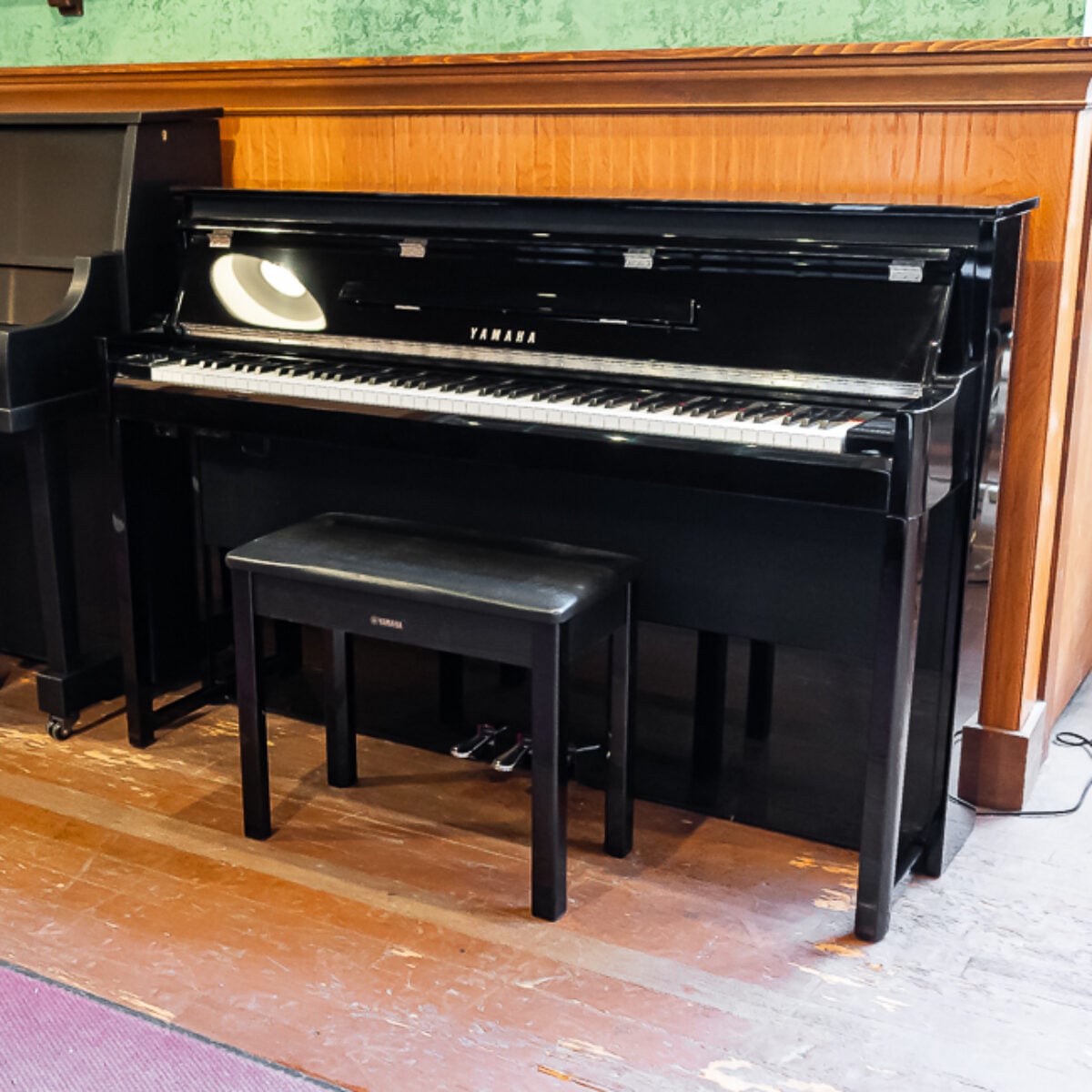 Yamaha U1 upright piano in polished ebony finish, featuring a top-quality action and a matching bench for ultimate playability.
