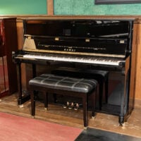 Kawai upright piano with polished ebony finish and matching bench, showcasing exquisite craftsmanship and tonal quality.